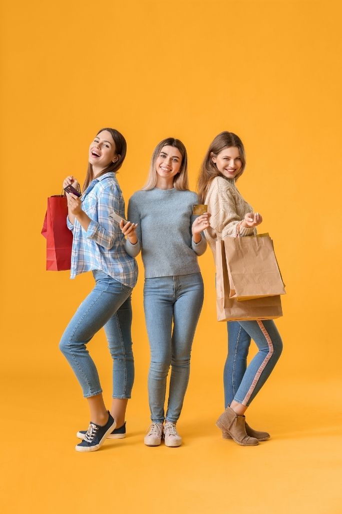 3 young women holding Visa gift cards & shopping bags