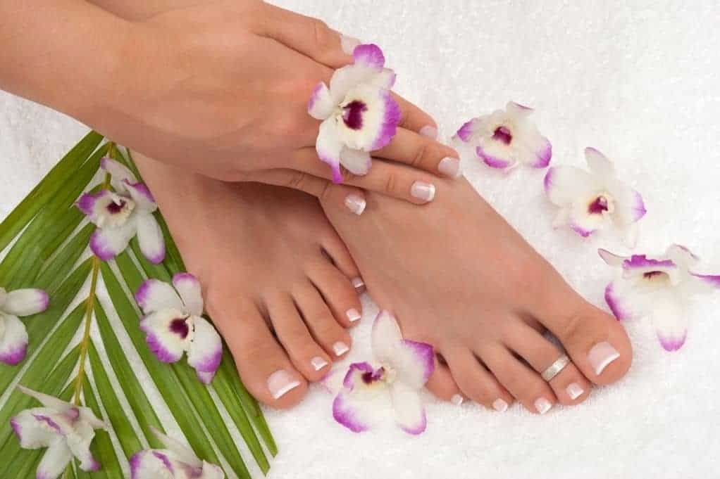 Woman touching her manicured feet, surrounded by flowers