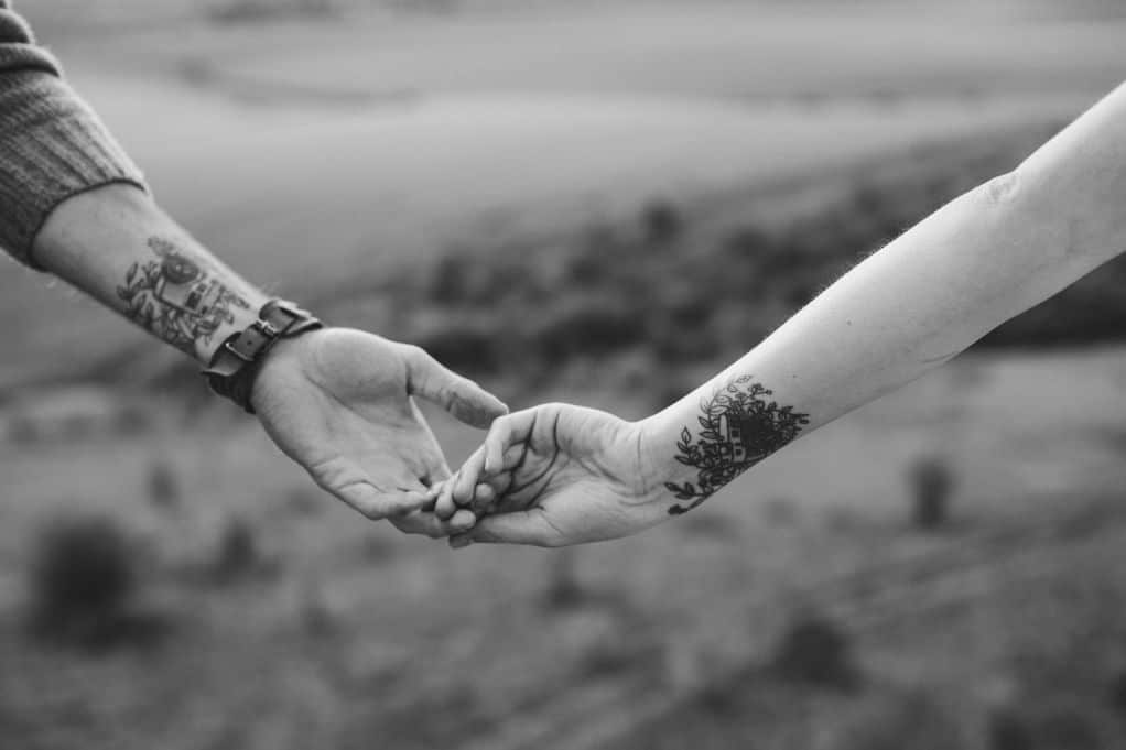 Man and women holding hands, both with tattoos