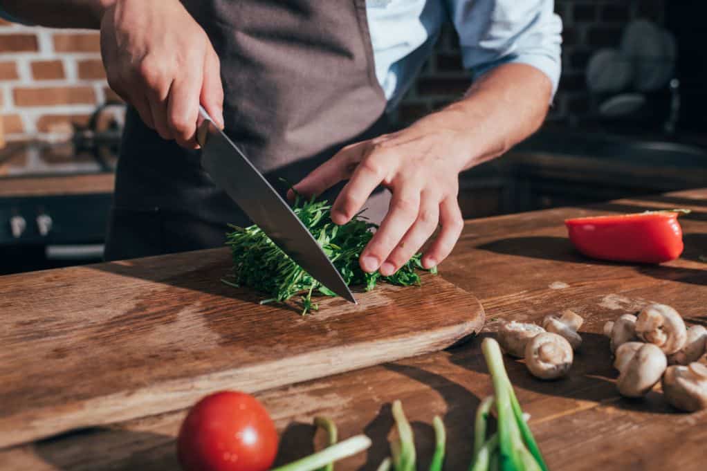 Man cutting greens on chopping board