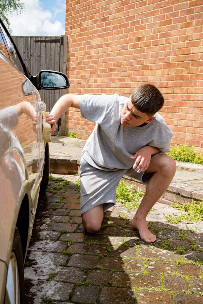 teenage boy washing a car