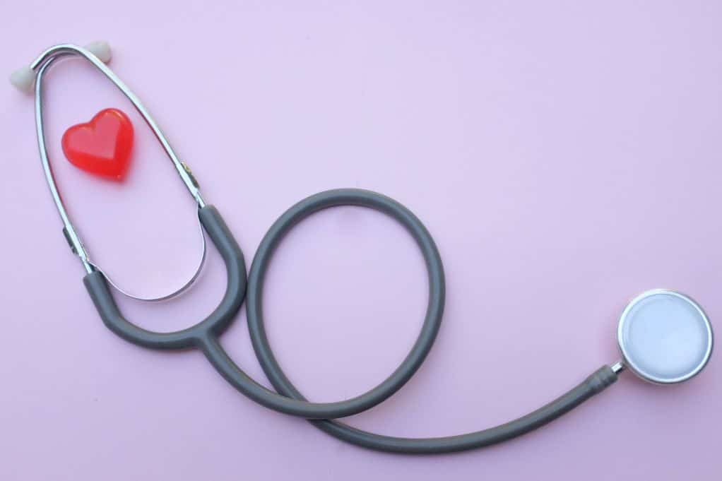 stethoscope & red heart laying on liliac background