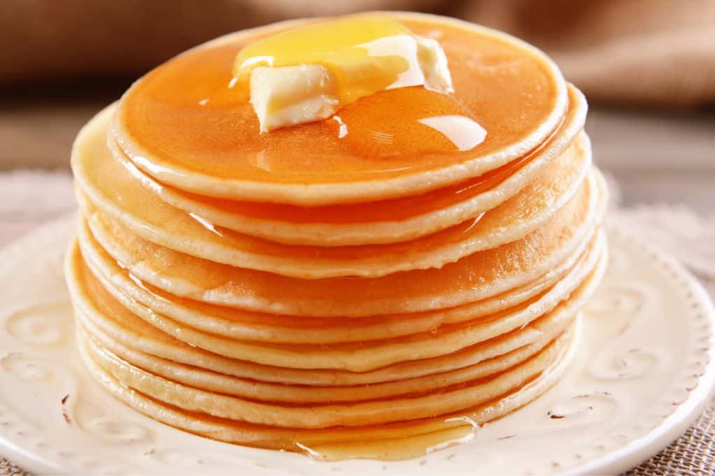 stack of pancakes topped with butter & syrup