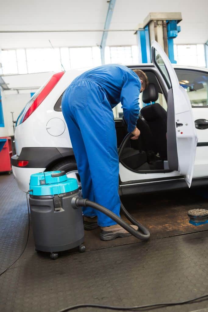 man vacuuming the interior of a car