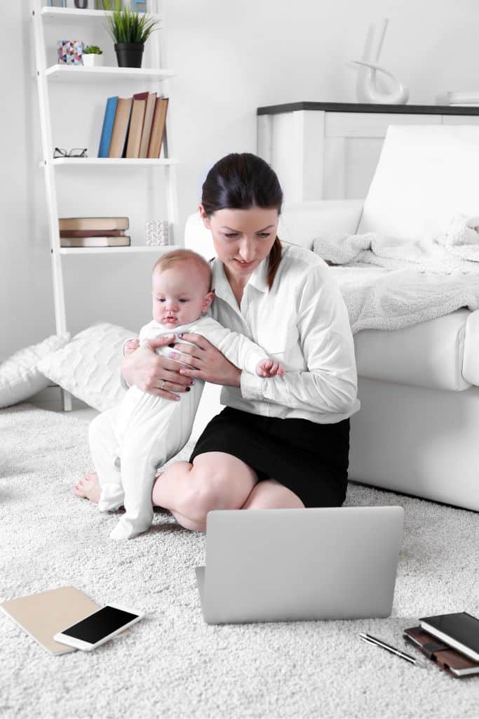 mom working while holding baby