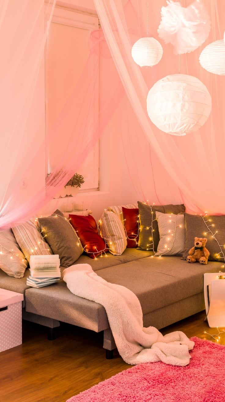 a pink bedroom with fairy lights